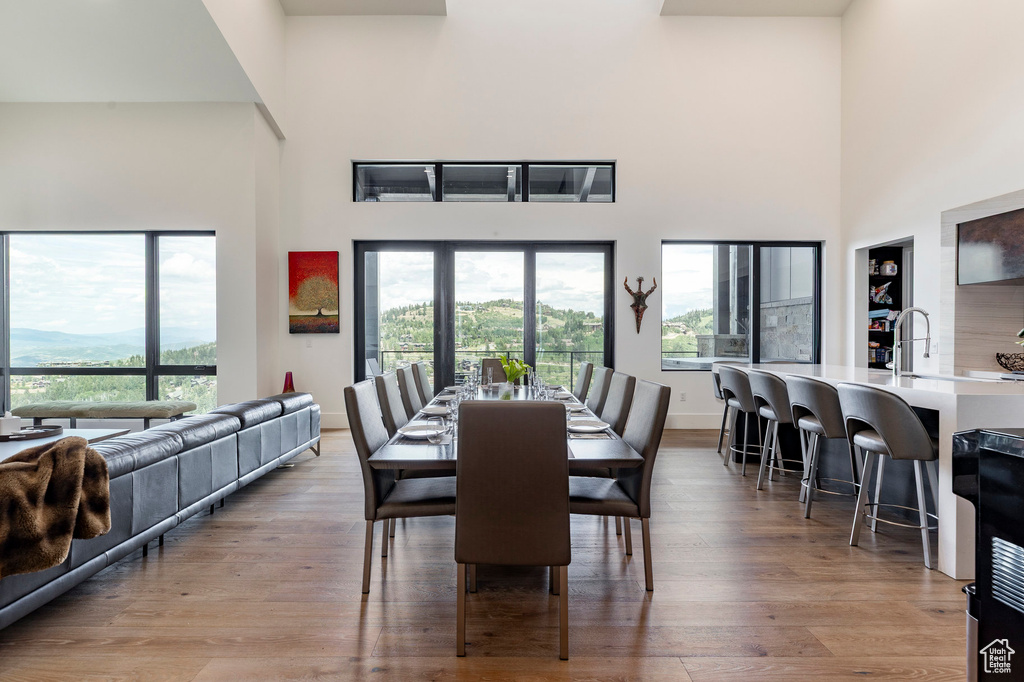 Dining area with a high ceiling, light wood-style flooring, and healthy amount of natural light