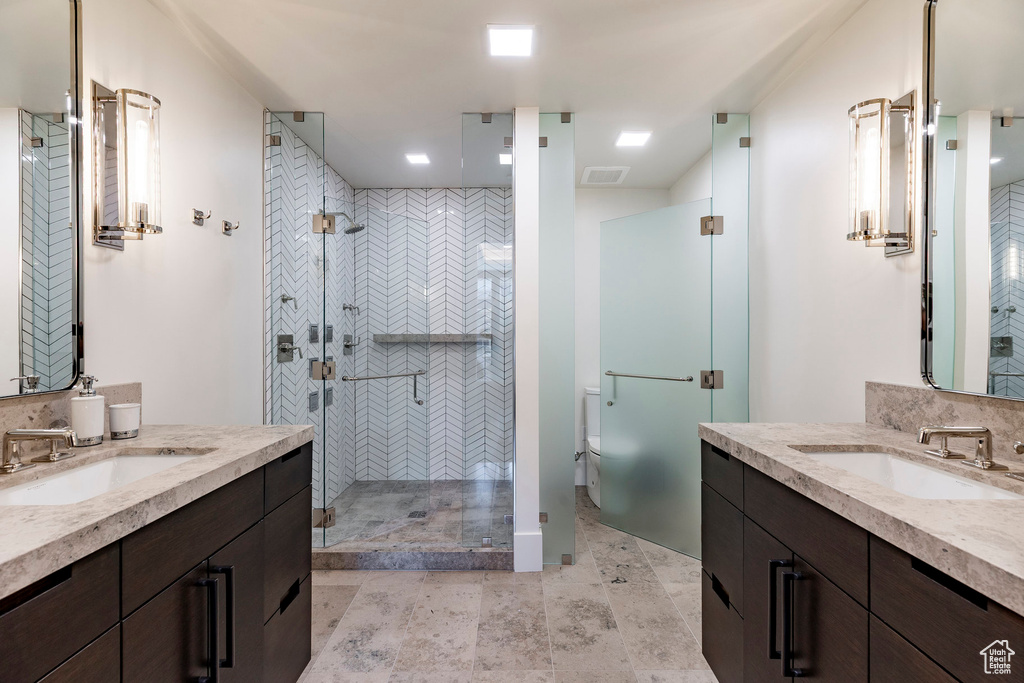 Full bathroom featuring two vanities and a stall shower