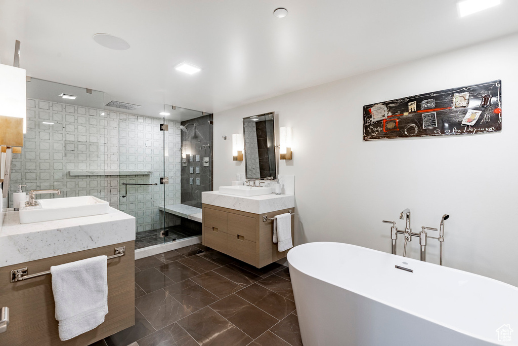 Full bathroom with two vanities, a stall shower, a freestanding bath, and marble finish floors