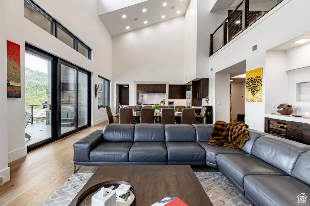 Living room featuring light wood-type flooring, a high ceiling, and recessed lighting