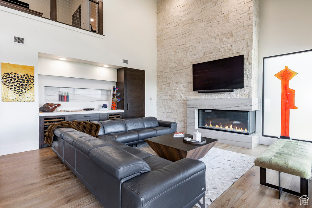 Living area with wood finished floors, a fireplace, a towering ceiling, and wine cooler