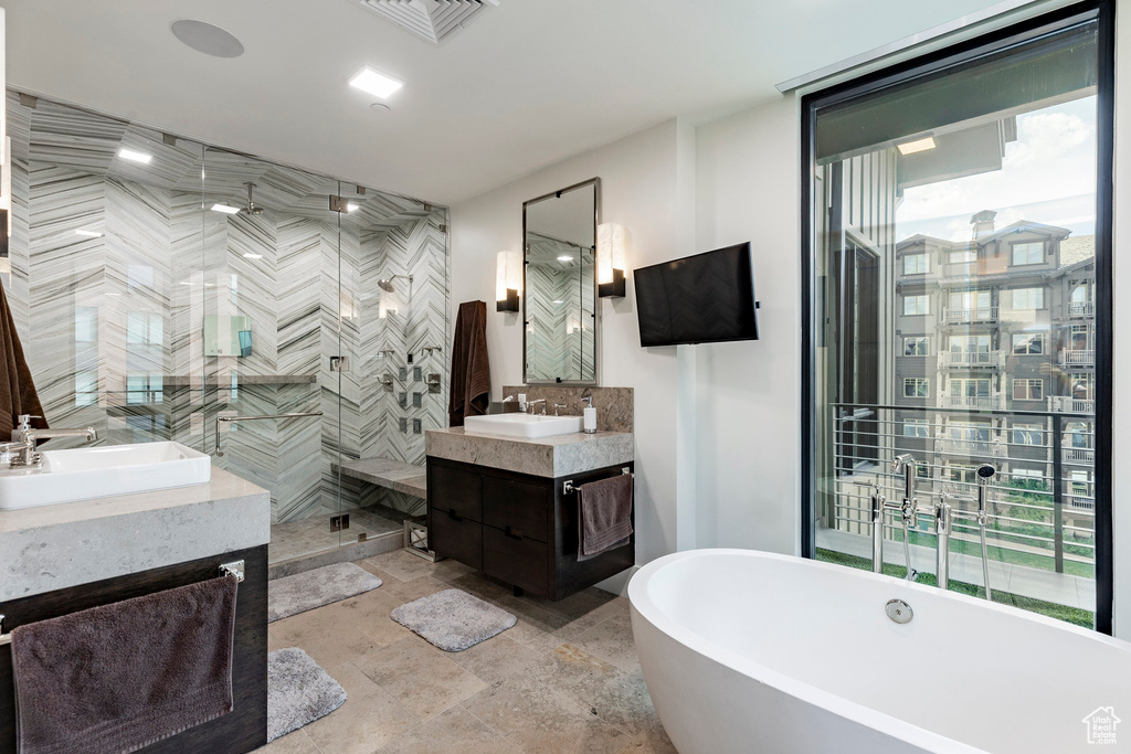 Bathroom featuring two vanities, a shower stall, and a freestanding tub