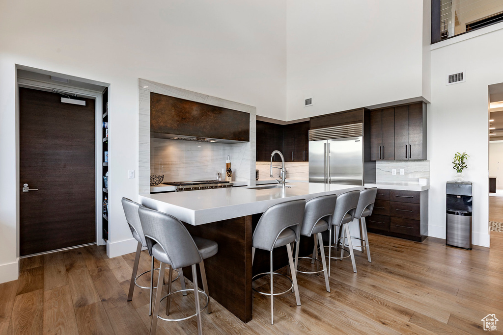 Kitchen featuring a high ceiling, light countertops, a kitchen breakfast bar, and dark brown cabinetry