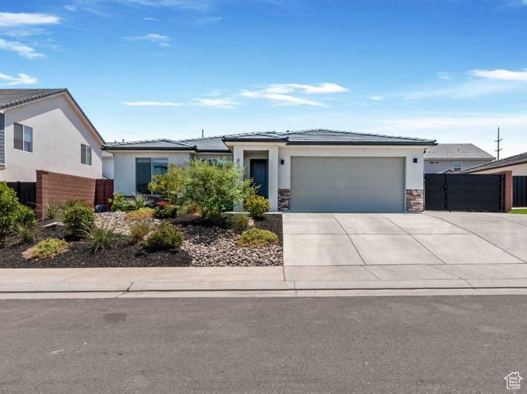 Prairie-style home with an attached garage, concrete driveway, and stucco siding