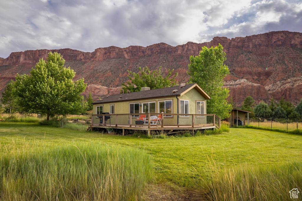 Back of house with a deck with mountain view, a chimney, and a yard