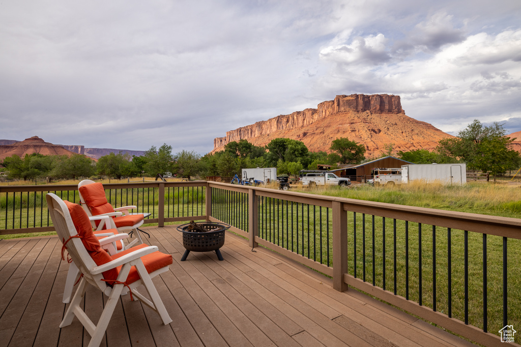 Wooden terrace with a fire pit, a mountain view, and a yard
