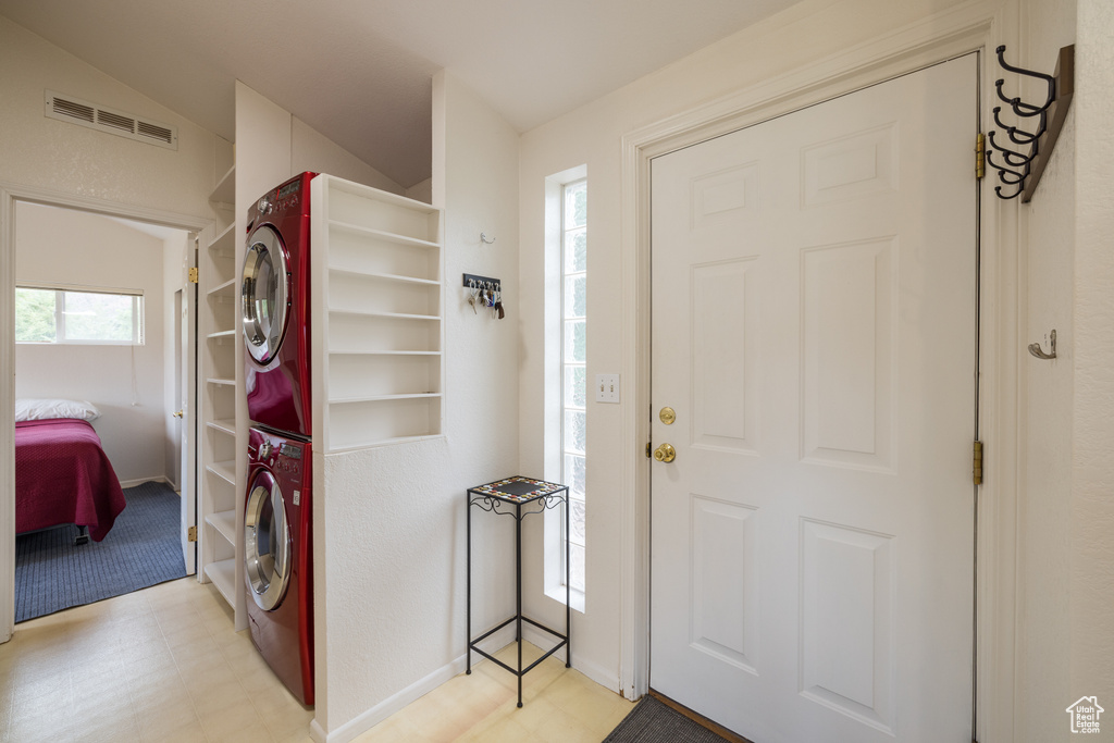 Foyer featuring estacked washer and dryer, light flooring, and lofted ceiling