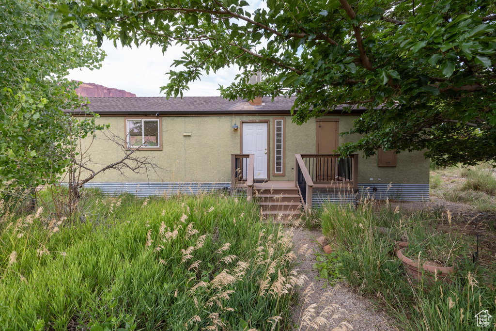 View of front of home featuring stucco siding and a shingled roof