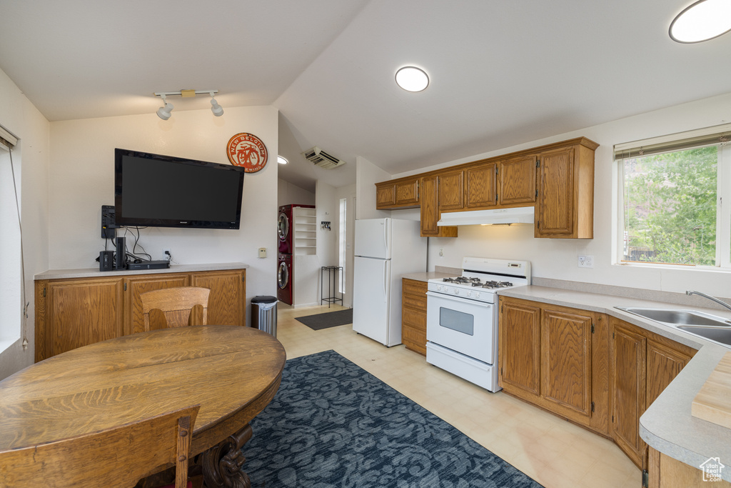 Kitchen with white appliances, light floors, lofted ceiling, light countertops, and under cabinet range hood