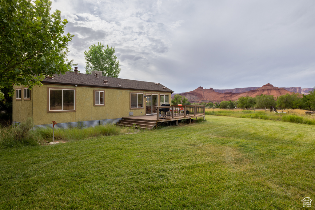 Back of house with a deck and a lawn