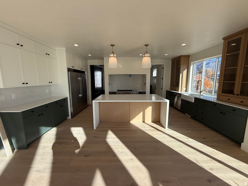 Kitchen with a center island, stainless steel appliances, decorative backsplash, hanging light fixtures, and recessed lighting