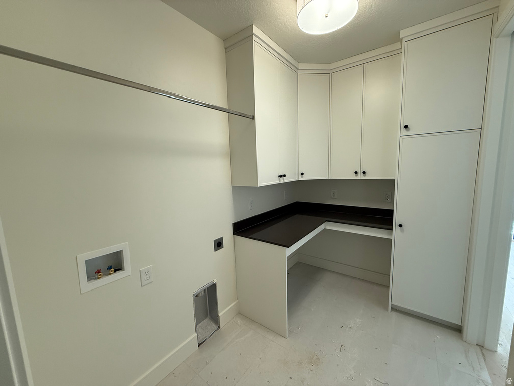 Washroom featuring electric dryer hookup, cabinet space, concrete floors, a textured ceiling, and washer hookup
