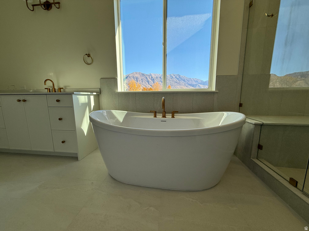 Full bathroom with vanity, a soaking tub, a mountain view, and tile walls