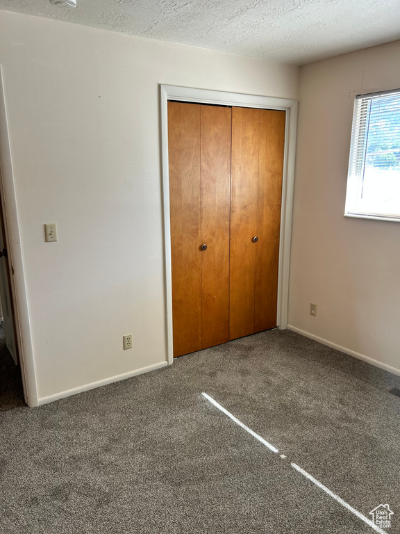 Unfurnished bedroom with carpet floors, a closet, and a textured ceiling
