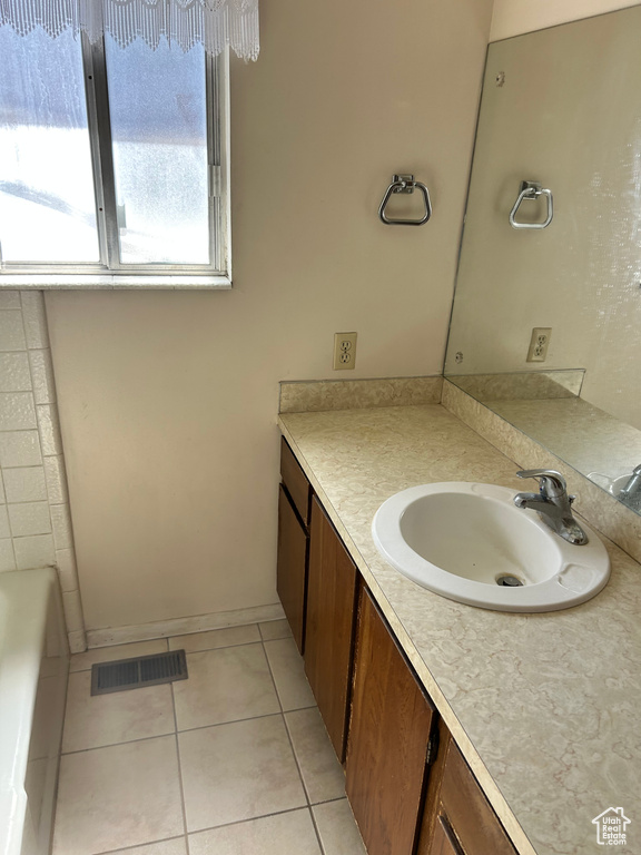 Bathroom featuring vanity, tile patterned floors, and a bath