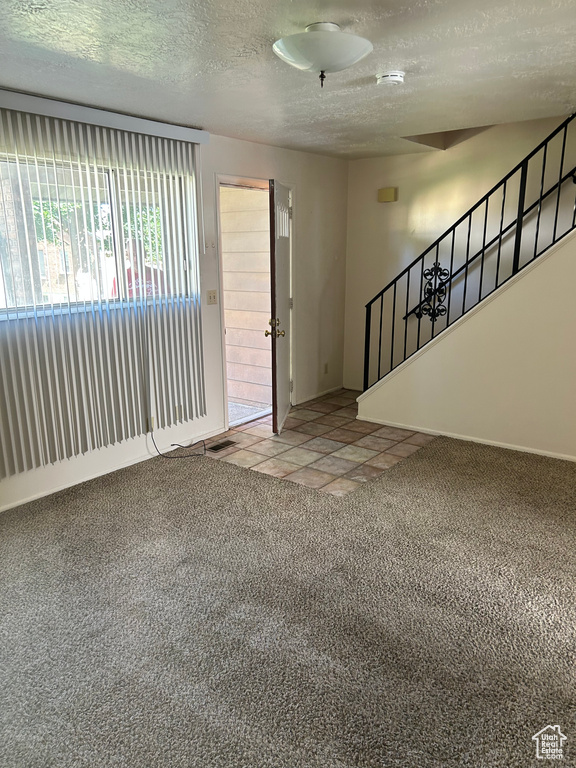 Entryway featuring light colored carpet, a textured ceiling, and stairs