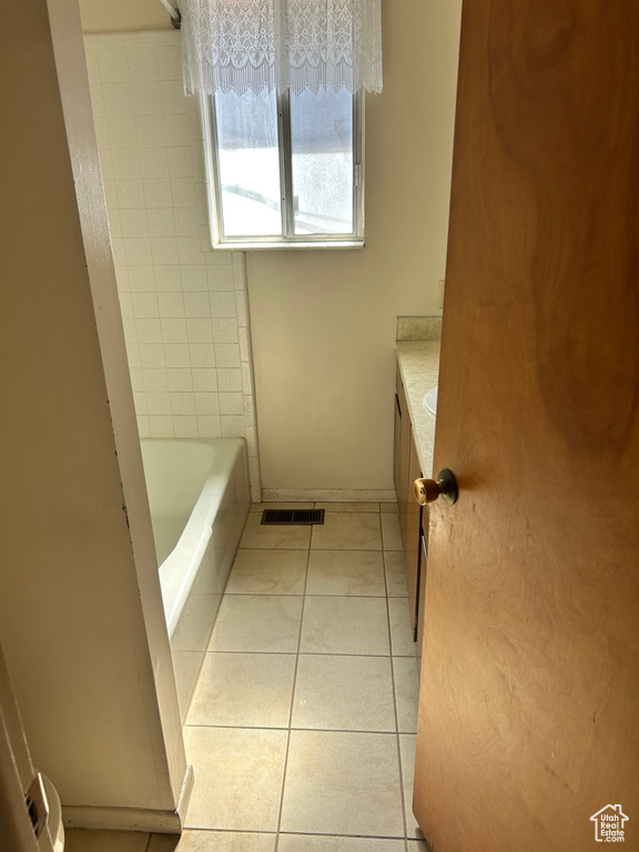 Bathroom with tile patterned flooring, vanity, and a bath