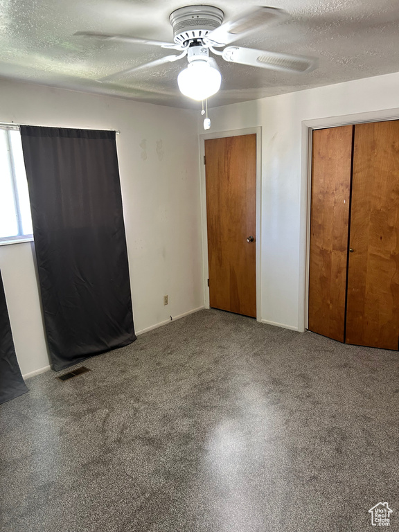 Unfurnished bedroom with a textured ceiling, carpet floors, and ceiling fan