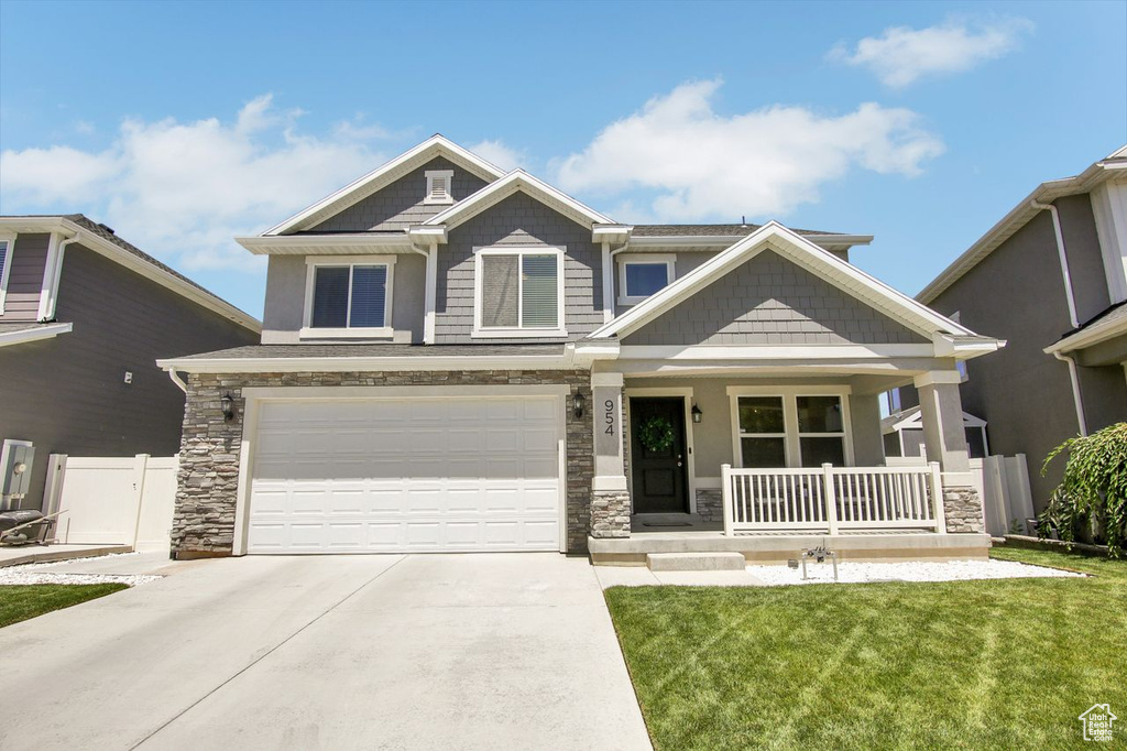 Craftsman-style home featuring covered porch, stone siding, concrete driveway, and an attached garage