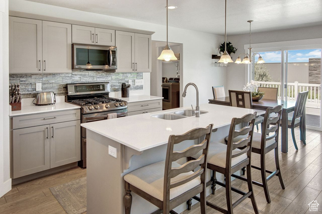 Kitchen featuring separate washer and dryer, stainless steel appliances, decorative backsplash, light wood finished floors, and light countertops