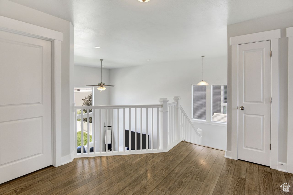 Hall with an upstairs landing, wood finished floors, and recessed lighting