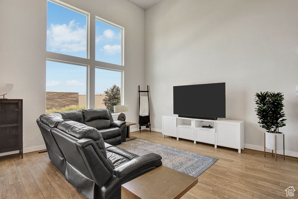 Living room featuring light wood-style flooring and a towering ceiling
