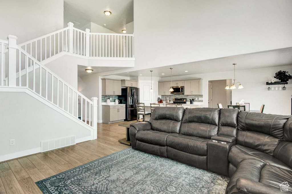 Living area featuring light wood-type flooring, stairs, a towering ceiling, a chandelier, and recessed lighting