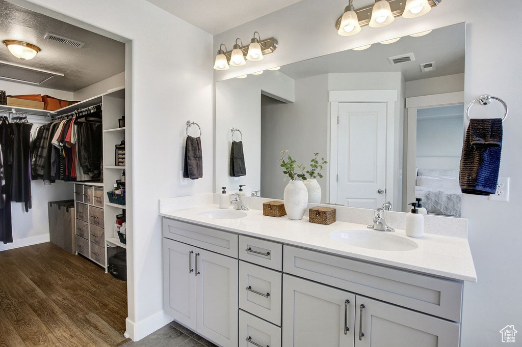 Full bathroom with double vanity, wood finished floors, and a spacious closet