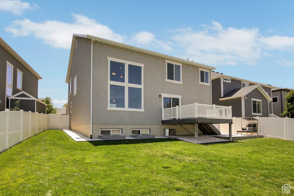 Rear view of house featuring a deck, a fenced backyard, and stucco siding