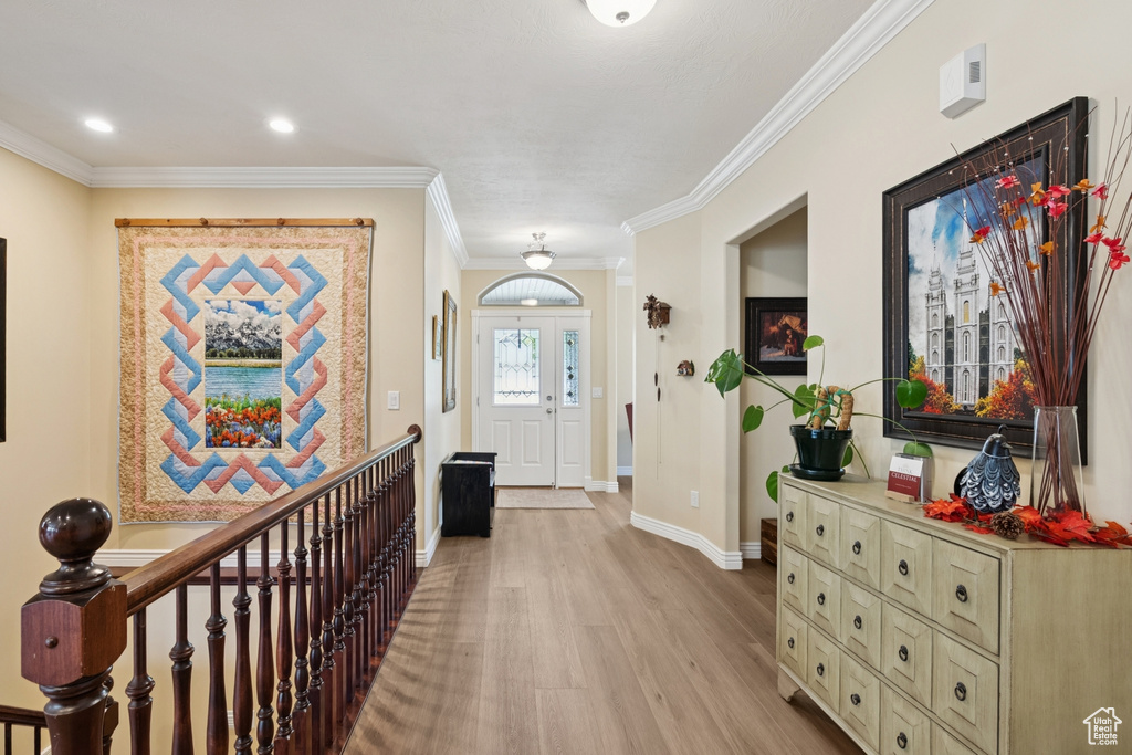 Entryway featuring light wood-type flooring, crown molding, and recessed lighting