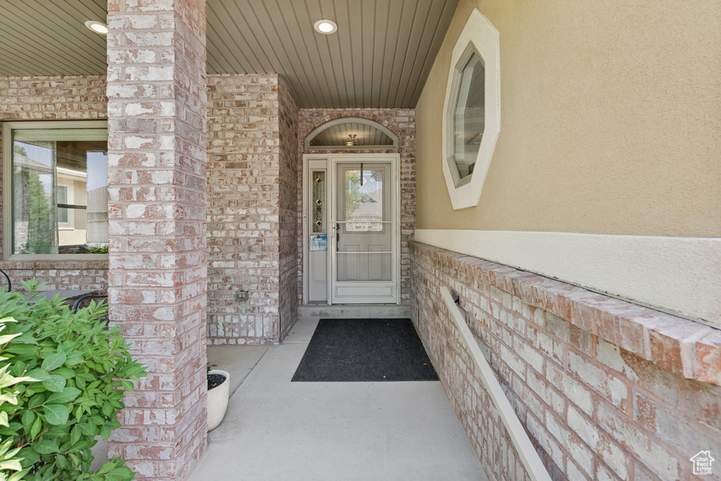 Entrance to property featuring brick siding, stucco siding, and a porch