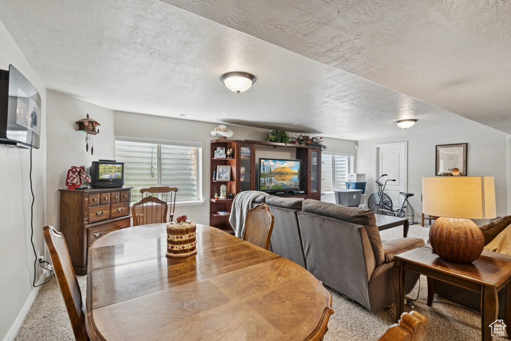 Dining space with light carpet and a textured ceiling