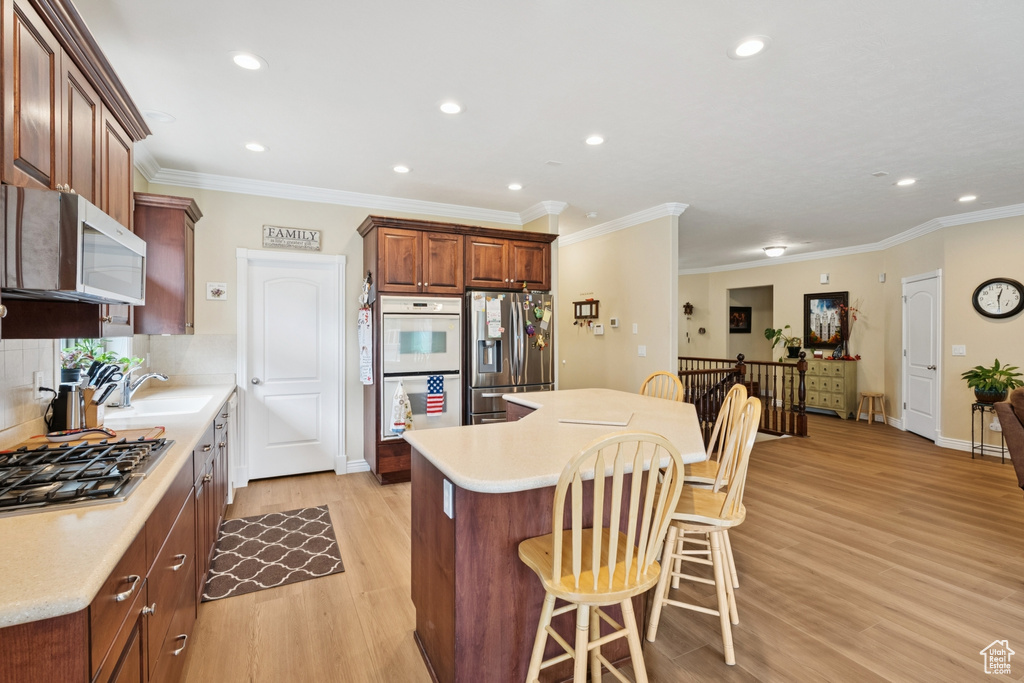Kitchen featuring a breakfast bar area, stainless steel appliances, recessed lighting, light wood finished floors, and light countertops