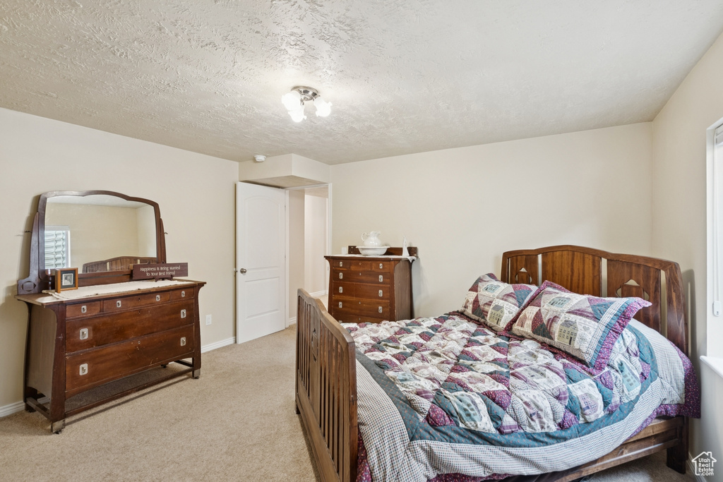 Bedroom featuring light colored carpet and a textured ceiling