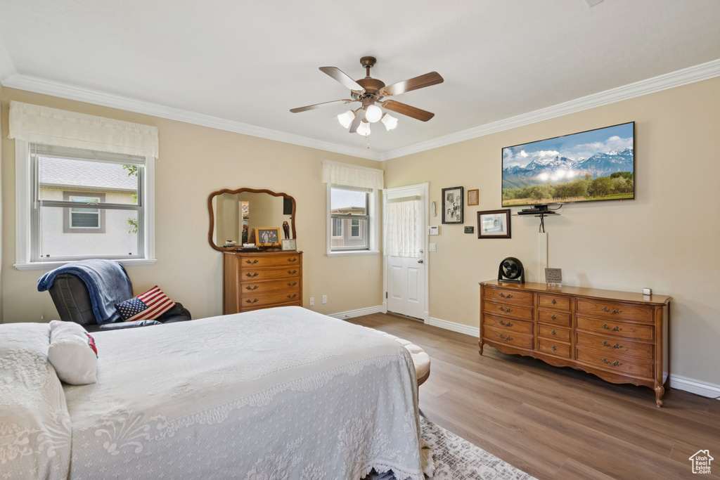 Bedroom with ornamental molding, wood finished floors, and a ceiling fan