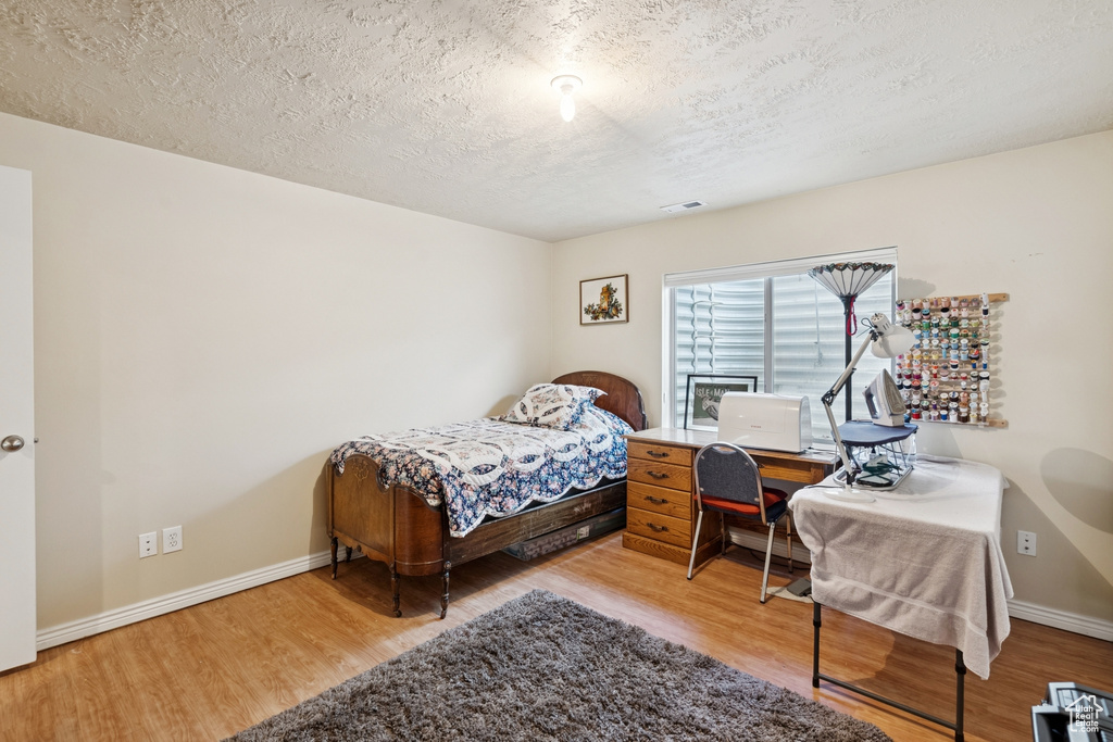 Bedroom featuring wood finished floors and a textured ceiling