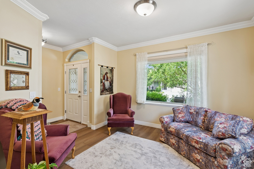 Living area with crown molding and wood finished floors