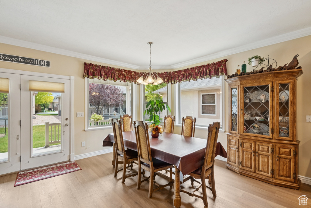 Dining room featuring light wood finished floors, a chandelier, and crown molding