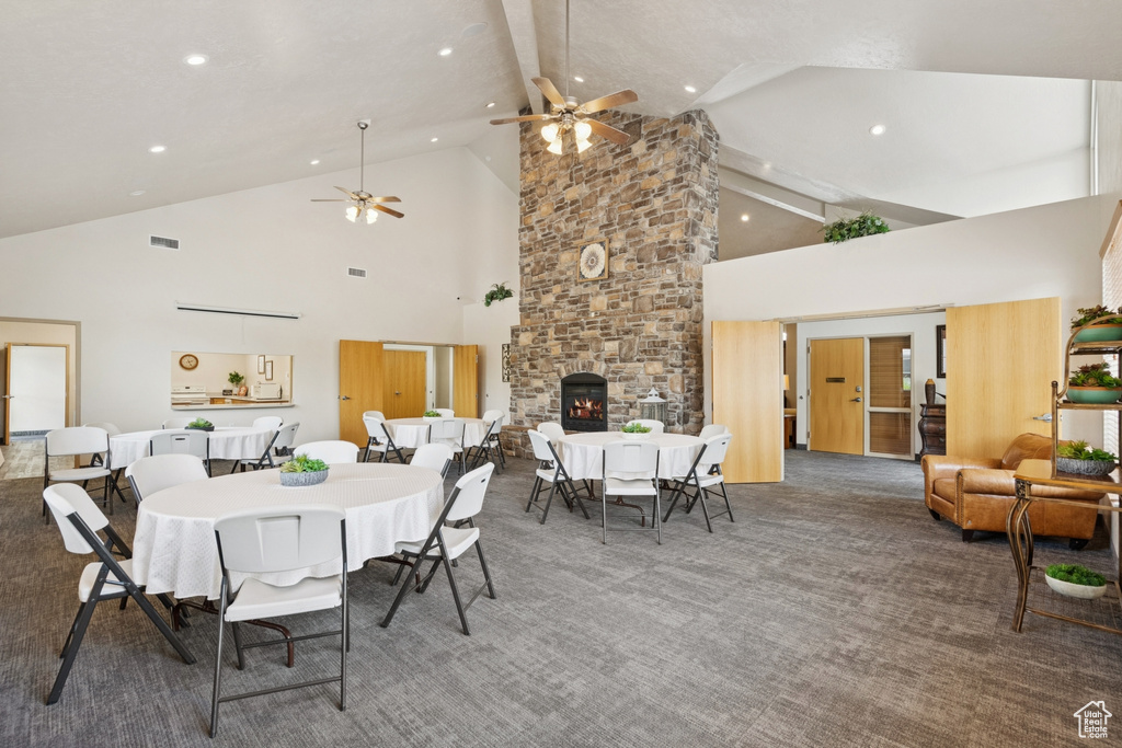 Dining room featuring high vaulted ceiling, a ceiling fan, recessed lighting, carpet floors, and a large fireplace