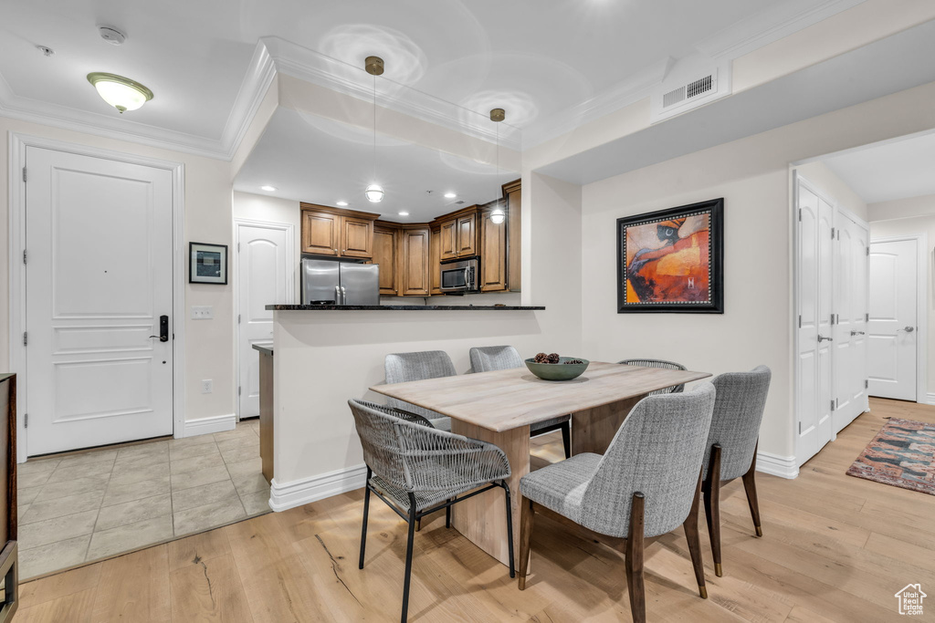Dining area featuring light wood-style flooring, ornamental molding, and recessed lighting