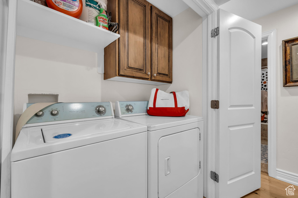 Laundry area featuring cabinet space, washing machine and dryer, and light wood finished floors