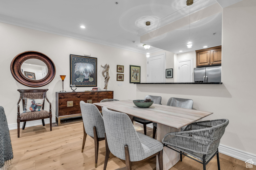Dining space with ornamental molding, light wood-style flooring, and recessed lighting