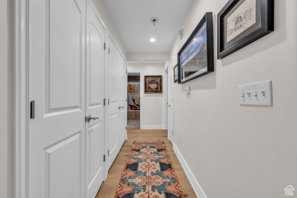 Hallway with light wood-type flooring and recessed lighting