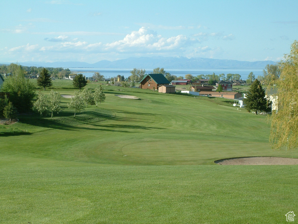 Surrounding community featuring view of golf course, a lawn, and a water and mountain view