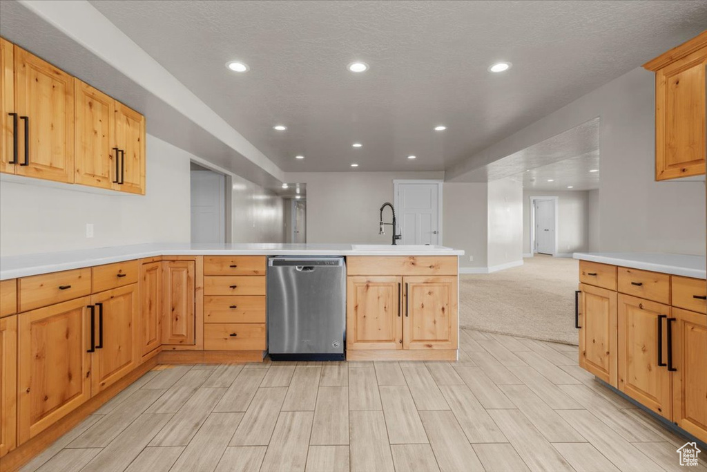 Kitchen with stainless steel dishwasher, recessed lighting, a peninsula, light countertops, and light wood-style floors