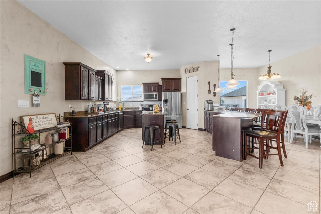 Kitchen featuring a breakfast bar, stainless steel appliances, dark brown cabinetry, and a center island
