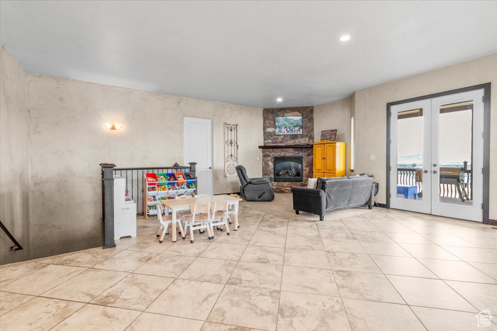 Living area featuring french doors, a stone fireplace, recessed lighting, and light tile patterned flooring