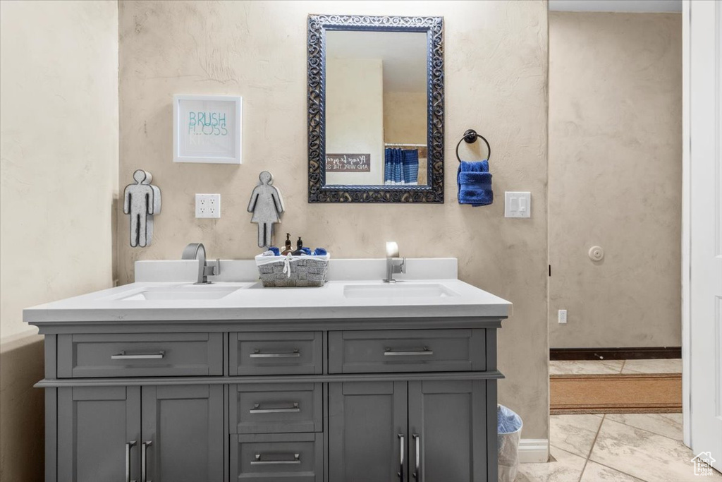 Full bath featuring double vanity and marble look tile flooring