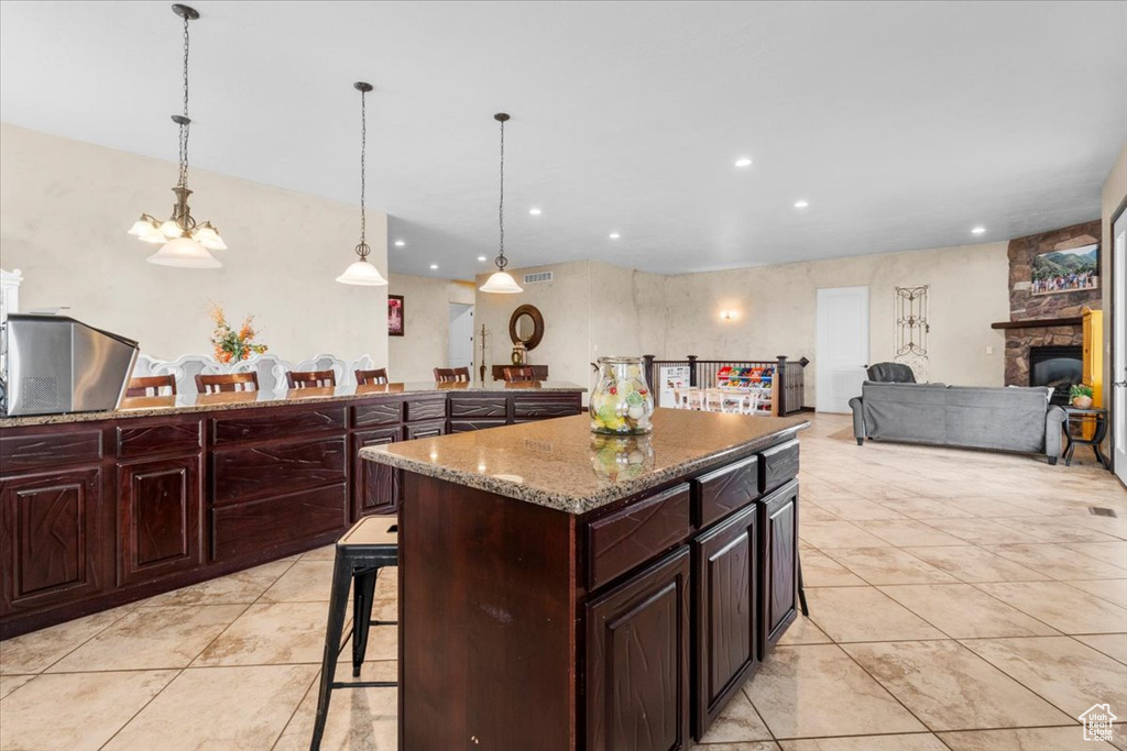Kitchen with a breakfast bar, recessed lighting, light tile patterned floors, light stone counters, and a kitchen island