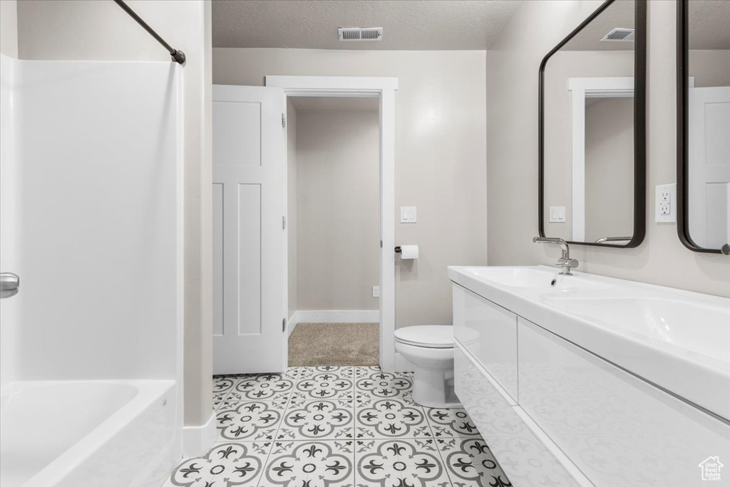 Full bathroom with double vanity, a textured ceiling, and tub / shower combination